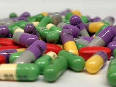Colorful prescription capsules and round tablets scattered on a white surface